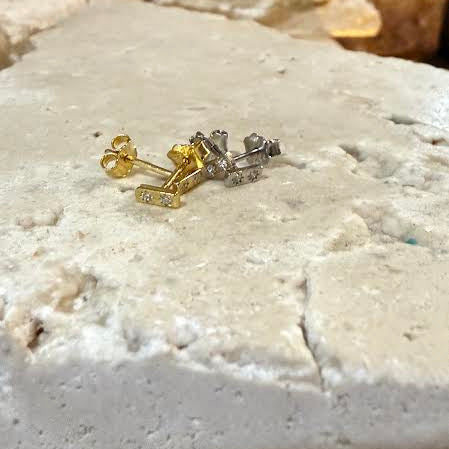 Gold and silver earrings on a textured stone surface
