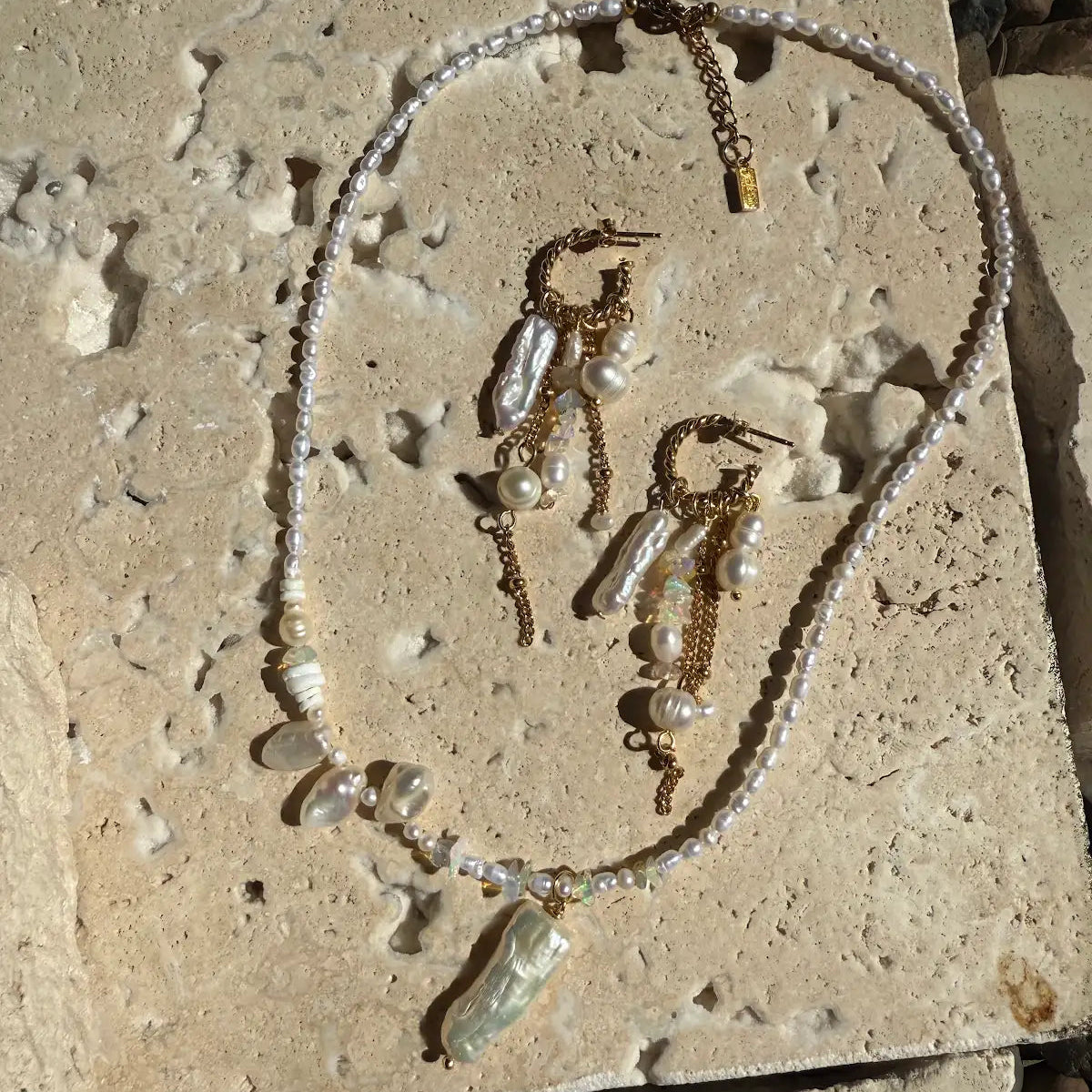 Jewelry set including necklace and earrings on a textured stone surface