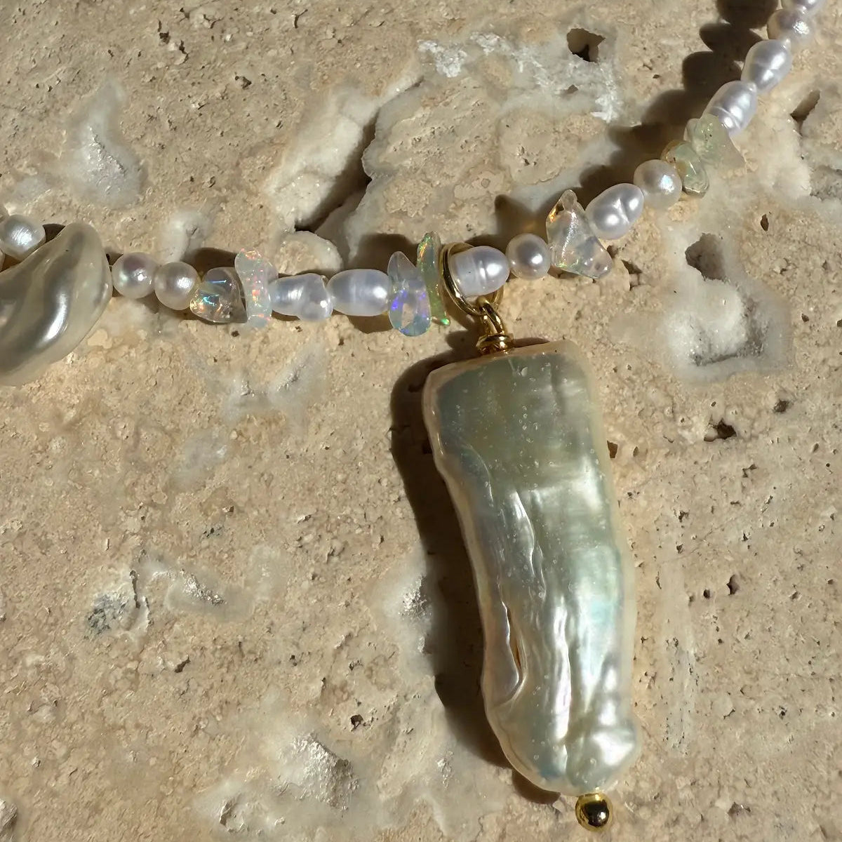 Pearl necklace with a large baroque pearl pendant on a sandy background