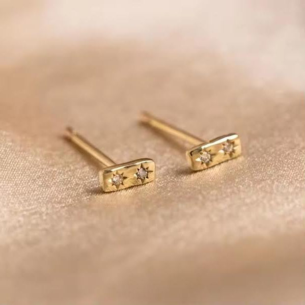 Gold earrings with small diamonds on a beige background