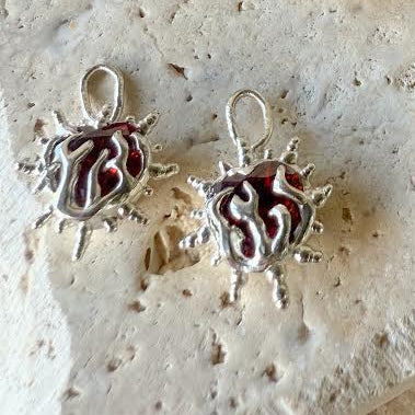 Collection of silver and gold jewelry with red stones on a textured surface