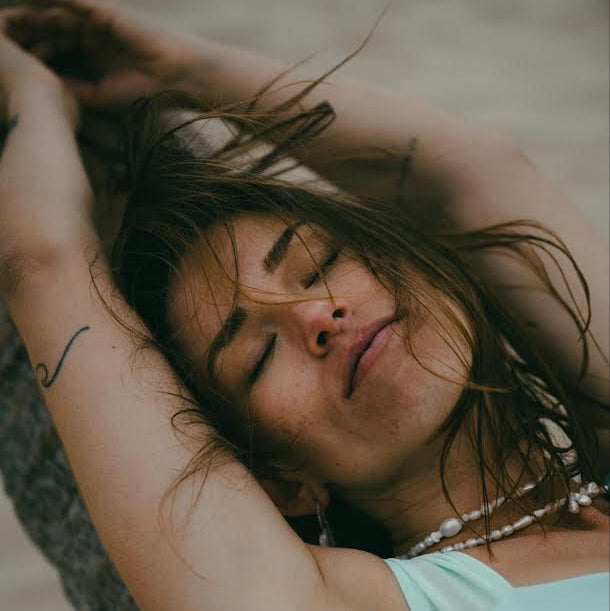 Woman with closed eyes leaning against a tree