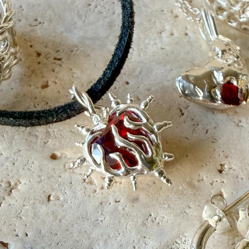 Silver pendant with red center on a textured surface
