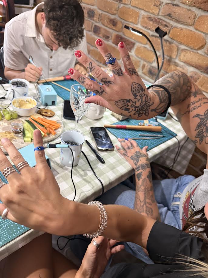 Person with tattoos showing off their hands at a table with various items.lostwax