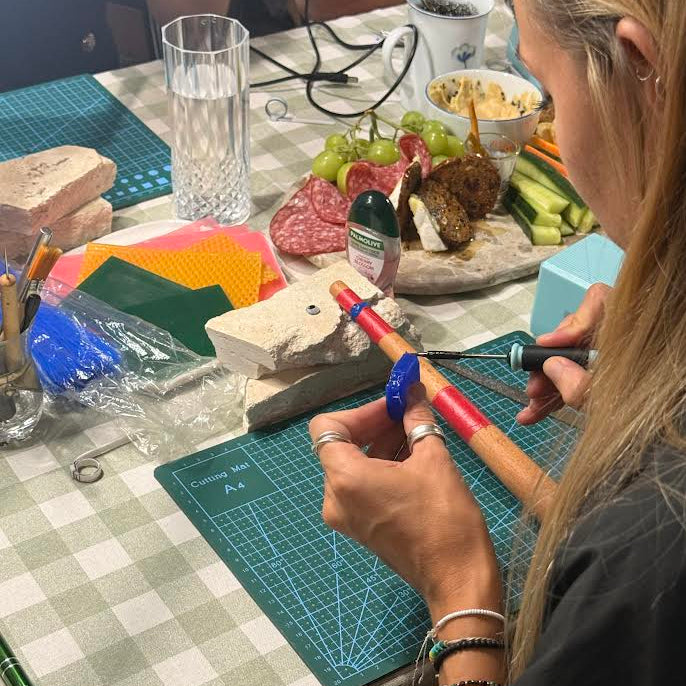 Person working on a lostwax ring with tools and materials on a checkered tablecloth.